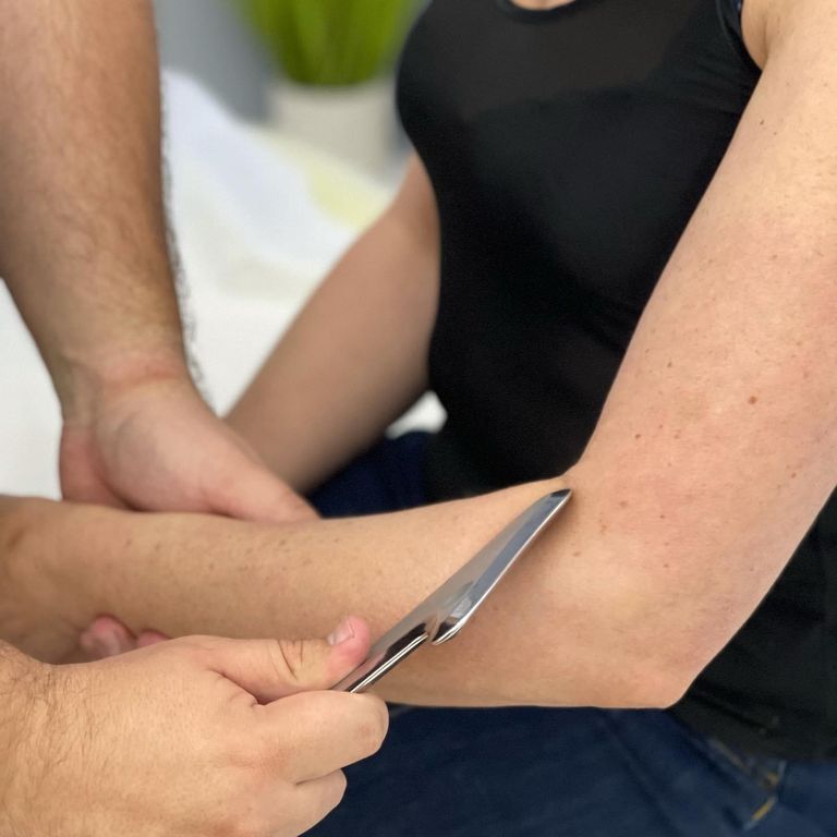 Instrument-assisted soft tissue treatment being applied to a client's forearm
